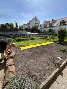 Gärtnerin beim Verlegen von frischem Rollrasen auf vorbereiteten Boden.