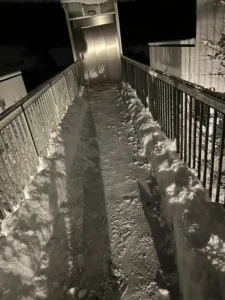 Ein geräumter Weg mit Schnee links und rechts der Laufspur, beleuchtet bei Nacht.